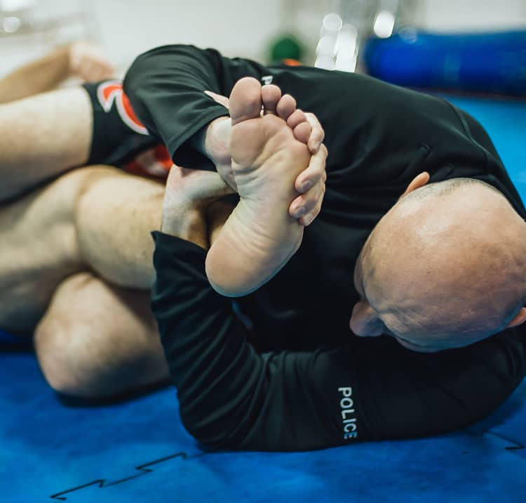 グラウンドポジションで関節技をかける格闘技トレーニングの場面。