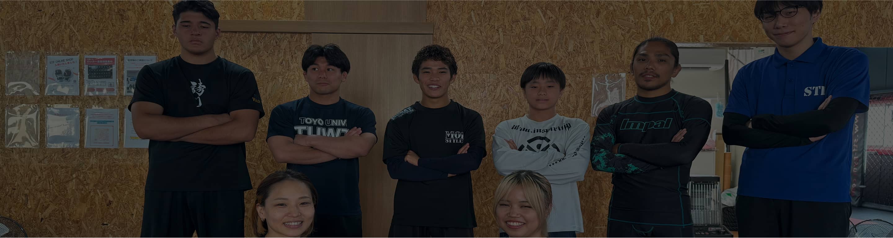 ジムでトレーニングをしているメンバーのグループ写真。全員がカジュアルなスポーツウェアを着て笑顔を見せている。