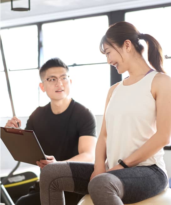 トレーナーと笑顔で話す女性のフィットネスカウンセリング